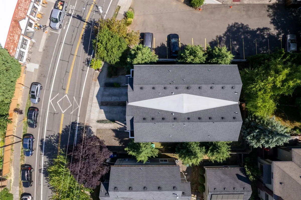 An exterior view capturing the rooftops of nearby buildings, with lush greenery and street scenes below. The image conveys the vibrancy of the neighborhood and offers a sense of the urban environment just outside the home.