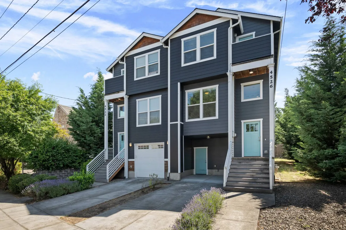 A welcoming exterior view of the townhouse featuring modern architecture, large windows, and a spacious front porch with steps. The surrounding greenery hints at a family-friendly, community-oriented neighborhood, inviting families to gather and enjoy the outdoors.